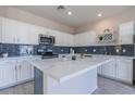 Kitchen features stainless steel appliances, blue backsplash, a kitchen island and white cabinets at 29891 N Desert Angel Dr, San Tan Valley, AZ 85143