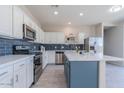Well-equipped kitchen boasts stainless steel appliances, blue backsplash, an island, and sleek white cabinets at 29891 N Desert Angel Dr, San Tan Valley, AZ 85143