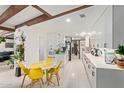 Open-concept kitchen features modern white cabinets, a tiled backsplash, and a cozy breakfast nook with bright yellow chairs at 301 W Royal Palm Rd, Phoenix, AZ 85021