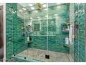 Modern glass shower featuring green tile, built-in shelves, and pebble flooring at 301 W Royal Palm Rd, Phoenix, AZ 85021