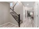 Hallway with staircase, gray tone, wood-look tile flooring, and white walls leading into an open-concept living space at 5407 S Tatum Ln, Gilbert, AZ 85298