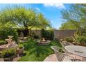 Serene backyard featuring a fire pit, lush green lawn, and mature landscaping at 7291 E Eagle Feather Rd, Scottsdale, AZ 85266