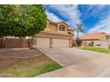 A tan house featuring a well-manicured lawn and three-car garage at 7460 E Kiowa Ave, Mesa, AZ 85209