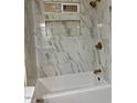Modern bathroom with white marble tiling, gold fixtures, and a shower/tub combo at 1149 S 98Th St, Mesa, AZ 85208