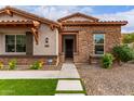 Inviting entryway of home with stone accents, manicured landscaping, and artificial turf at 13367 W Jesse Red Dr, Peoria, AZ 85383