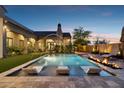 Backyard pool area with built-in lounge chairs, water features, a fireplace, and lush landscaping at 13750 E Yucca St, Scottsdale, AZ 85259