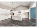 Bright, open kitchen with white cabinets, a large island, and modern pendant lighting at 13850 W Weaver Ct, Litchfield Park, AZ 85340