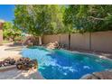 Sparkling pool with a rock waterfall feature surrounded by lush greenery, perfect for relaxation at 1811 S Brentwood Pl, Chandler, AZ 85286