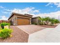 Attractive single-story home with brick paved driveway and desert landscaping on a sunny day at 18453 W Elwood St, Goodyear, AZ 85338