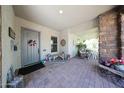 Cozy front porch featuring brick flooring, a brick pillar, a seating area, and decorative floral arrangements at 20421 W Legend Trl, Buckeye, AZ 85396