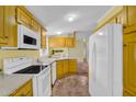 Well-lit kitchen featuring yellow cabinetry, white appliances, and ample counter space, offering a functional and inviting cooking area at 701 S 92Nd St, Mesa, AZ 85208
