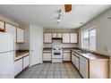 Bright kitchen with a window overlooking the backyard, tile floors, and plenty of white cabinets at 12233 W Aster Dr, El Mirage, AZ 85335