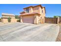 Two-story home with a large driveway featuring a two car garage and privacy gate at 1556 E Gabrilla Dr, Casa Grande, AZ 85122