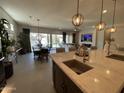Open-concept kitchen with a large island, granite countertops and modern pendant lighting overlooking the living area at 15801 W Cielo Grande Ave, Surprise, AZ 85387