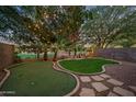 Lush backyard featuring a putting green, mature landscaping, string lights and a privacy fence at 3773 E Stampede Dr, Gilbert, AZ 85297