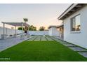 The backyard features well manicured synthetic lawn framed by stone pavers leading up to the home's back door at 4033 W Sharon Ave, Phoenix, AZ 85029