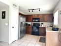 Functional kitchen featuring stainless steel appliances, dark wood cabinetry, and tile floors, ideal for cooking enthusiasts at 6538 W Nez Perce St, Phoenix, AZ 85043