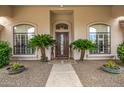 Elegant front entrance with a decorative glass door, flanked by lush greenery and decorative planters at 8603 E Aster Dr, Scottsdale, AZ 85260