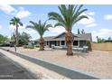 Attractive single-story home enhanced by well-maintained landscaping and stately palm trees at 1408 N 62Nd Pl, Mesa, AZ 85205