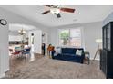 The cozy living room has an open floor plan, lots of light, plush carpet and an archway to the kitchen at 16139 N 171St Ln, Surprise, AZ 85388