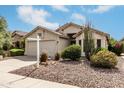 Single-story home with a two-car garage, xeriscaped front yard, and lush landscaping, creating curb appeal at 16424 S 46Th Way, Phoenix, AZ 85048