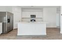 Kitchen island with sink, white cabinetry, stainless steel refrigerator, and wood-look floors at 18795 E Bruno Dr, Gold Canyon, AZ 85118