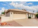 Beige two-car garage with decorative windows and a spacious driveway, complemented by desert landscaping at 24907 S Lakestar Dr, Sun Lakes, AZ 85248