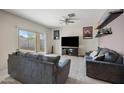 Open living room with a sliding glass door to the backyard and a large TV with console at 30963 W Columbus Ave, Buckeye, AZ 85396