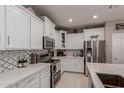 Well-equipped kitchen featuring white cabinets, stainless steel appliances, and stylish backsplash at 3823 S 101St Dr, Tolleson, AZ 85353