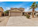 Two story home with desert landscaping, a large palm tree, and two car garage at 5220 W Desert Ln, Laveen, AZ 85339
