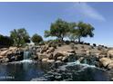 Scenic view of the The Bridges at Gilbert entrance featuring a rock waterfall and desert landscaping at 5420 S Mariposa Dr, Gilbert, AZ 85298