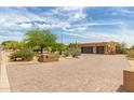 Expansive brick driveway leading to a tan home surrounded by desert landscaping at 8255 E Yearling Rd, Scottsdale, AZ 85255