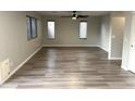 Spacious living room featuring modern wood flooring, ceiling fan, and several bright windows at 8514 S 49Th Dr, Laveen, AZ 85339
