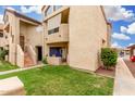 Exterior view of a two-story townhouse with tan stucco, green lawn, and private patio at 10301 N 70Th St # 223, Paradise Valley, AZ 85253