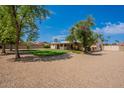 A tranquil backyard with verdant lawn, mature trees and a patio area for outdoor enjoyment and relaxation at 14627 N 55Th Pl, Scottsdale, AZ 85254