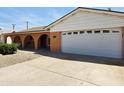 View of the garage side of this single-Gathering home, featuring a two-car garage, xeriscaping, and arched doorway at 2027 N 81St St, Scottsdale, AZ 85257