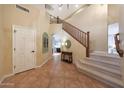 Inviting foyer with tile flooring, a staircase, and a view into the living area, creating a warm and open feel at 27803 N 59Th Dr, Phoenix, AZ 85083