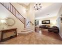 Spacious foyer with staircase, chandeliers, and a glimpse into the inviting living room with hardwood floors at 27803 N 59Th Dr, Phoenix, AZ 85083