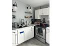 Well-lit kitchen boasts modern appliances, floating shelves, white cabinetry and a stainless steel sink at 3646 N 67Th Ave # 64, Phoenix, AZ 85033