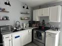 Well-lit kitchen boasts modern appliances, floating shelves, white cabinetry and a stainless steel sink at 3646 N 67Th Ave # 64, Phoenix, AZ 85033