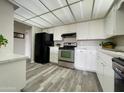 Well-lit kitchen featuring black appliances, wood-look flooring, and modern white cabinets at 425 S Parkcrest -- # 323, Mesa, AZ 85206