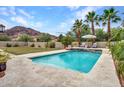 Backyard pool featuring a stone waterfall, lounge chairs, and lush landscaping with a mountain view at 5812 W Spur Dr, Phoenix, AZ 85083
