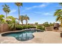 Backyard pool with a unique waterfall feature, mature landscaping, and an outdoor fireplace at 654 E County Down Dr, Chandler, AZ 85249
