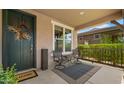 Inviting front porch with seating area, stylish outdoor rug, and decorative front door with a wreath at 10224 E Talameer Ave, Mesa, AZ 85212