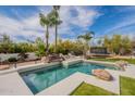 Inviting backyard pool and spa featuring rock waterfall, palm trees, and lush landscaping at 8502 E Santa Catalina Dr, Scottsdale, AZ 85255