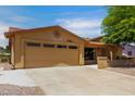 Tan home featuring a two car garage with a decorative sun ornament above the door at 922 S 80Th St, Mesa, AZ 85208