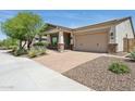 Inviting single-story home showcasing a manicured front yard with brick-paved driveway and desert-friendly landscaping at 11872 W Duane Ln, Peoria, AZ 85383
