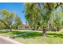 Charming single story home featuring mature landscaping, green shutters and a brick facade at 1562 W Las Palmaritas Dr, Phoenix, AZ 85021