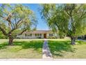 Charming single story home featuring mature landscaping, green shutters and a brick facade at 1562 W Las Palmaritas Dr, Phoenix, AZ 85021