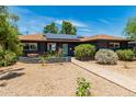 Inviting home with a well-manicured yard, solar panels, and a tidy walkway to the front door at 1814 W Thomas Rd, Phoenix, AZ 85015